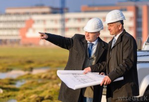 two-men-in-business-suits-and-white-hard-hats-pointing